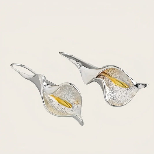 Pair of silver and gold leaf-shaped earrings on a light background