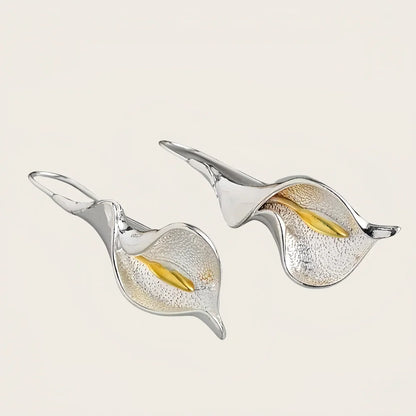 Pair of silver and gold leaf-shaped earrings on a light background
